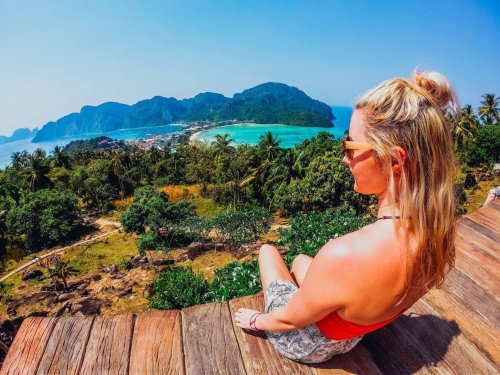 Girl sitting at Koh Phi Phi Thailand Viewpoint overlooking ocean and lush green Palm Trees