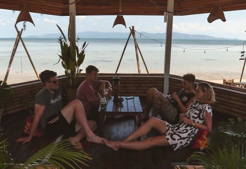 Group of friends sitting enjoying a drink at beach bar overlooking the ocean on the beach