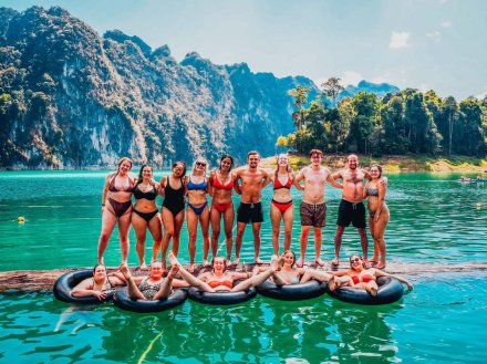 A group photo of people on a log and in doughnuts with breathtaking views at Khao Sok national park