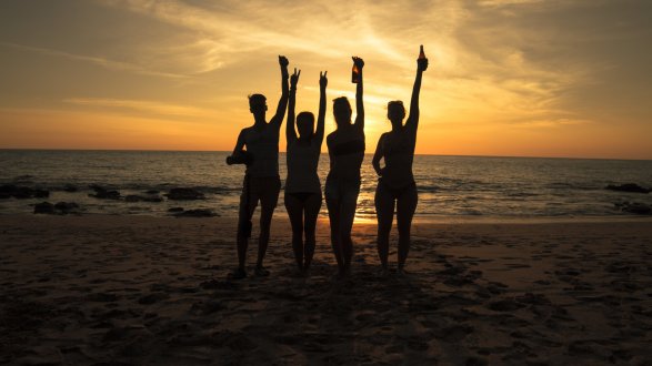 A group of four at the beach in Koh Lanta at sunset with their hands in the air 