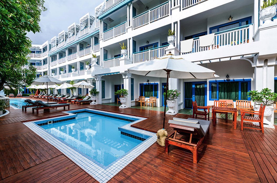 A shot of the outside area at the hotel in Phuket, Thailand showing two blue pools, sun loungers and tables with chairs. 