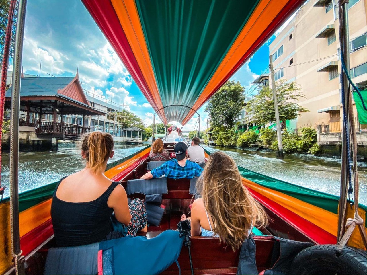 People riding down the river in a colourful longtail boat in Thailand