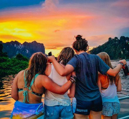A group of four admiring the stunning orange and pink sunset in Railay beach, Krabi, Thailand 