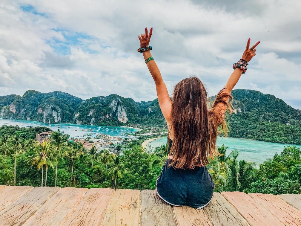 A girl at the top of the viewpoint in Koh Phi Phi, Thailand admiring the view of the crystal clear blue water and lush greenery 