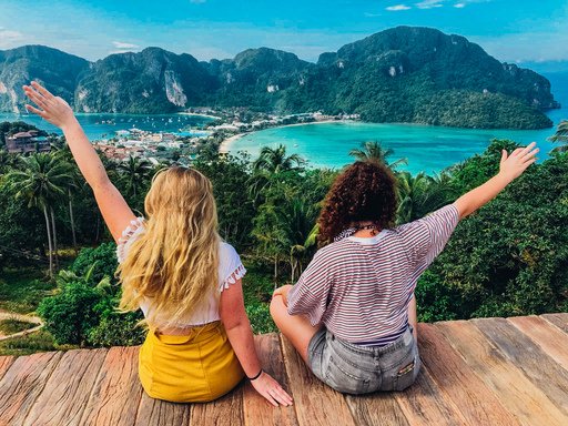 Two girls at the viewpoint in Koh Phi Phi, Thailand admiring the view of lush greenery, bright crystal clear sea and sunny blue sky  