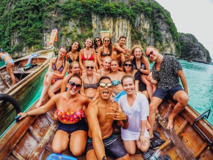 A group selfie on a long tail boat in Koh Phi Phi, Thailand showing the crystal clear water and famous cliff formations
