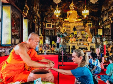 A girl being blessed by a monk at the temples in Bangkok Thailand 