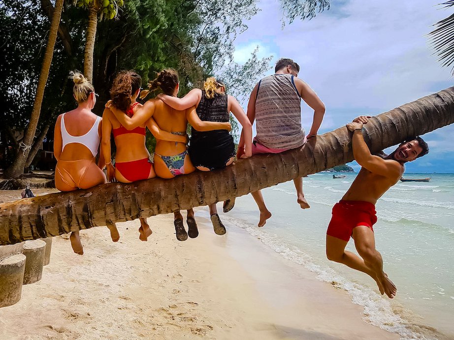 A group photo on a tree trunk at the beach in Koh Tao Thailand