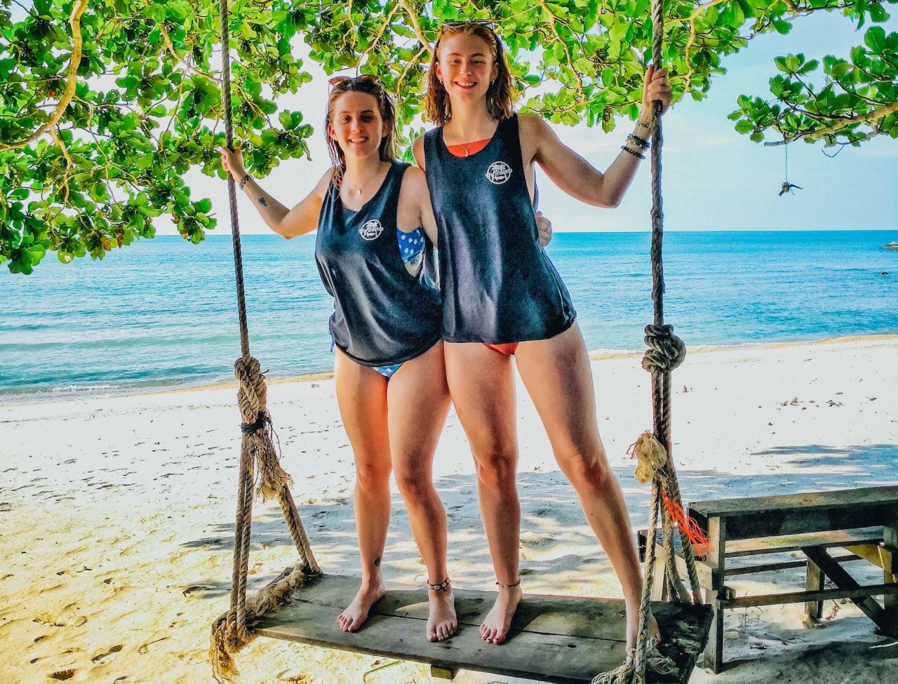 Two girls on a swing at the idyllic bottle beach Koh Phangan Thailand 